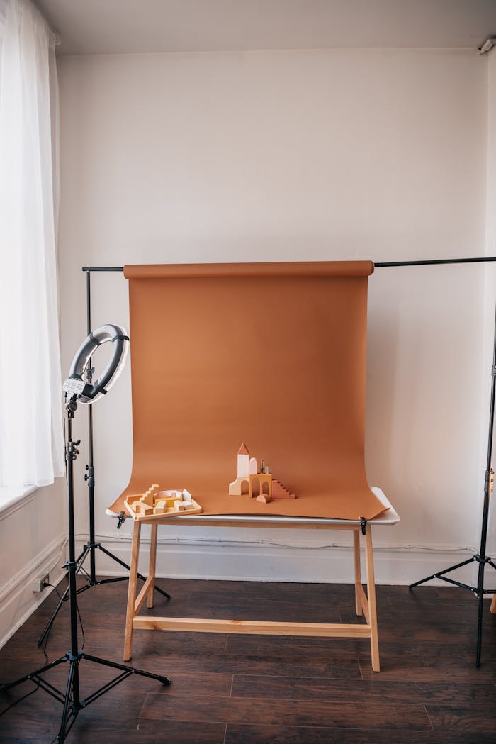 A clean studio setup featuring a brown paper backdrop on a wooden table with studio lights.